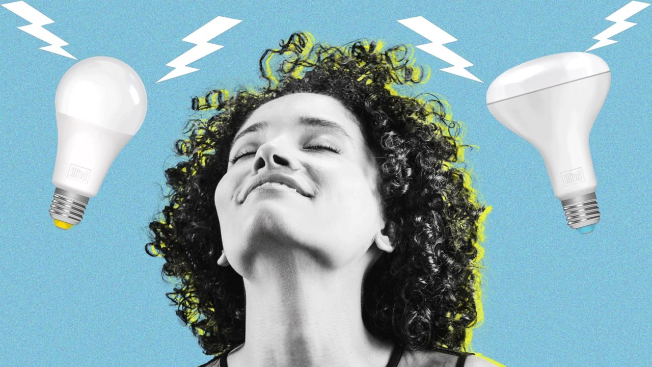 A woman with curly hair smiling with closed eyes, surrounded by animated lightning bolts and two energy-efficient light bulbs.